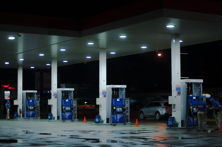 person taking a photo of blue and white gasoline station - The Bright Side of using Fossil Fuel in Modern Times